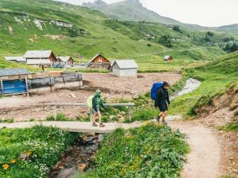 Der Weg führt vorbei an Blumenwiesen und Alphütten.